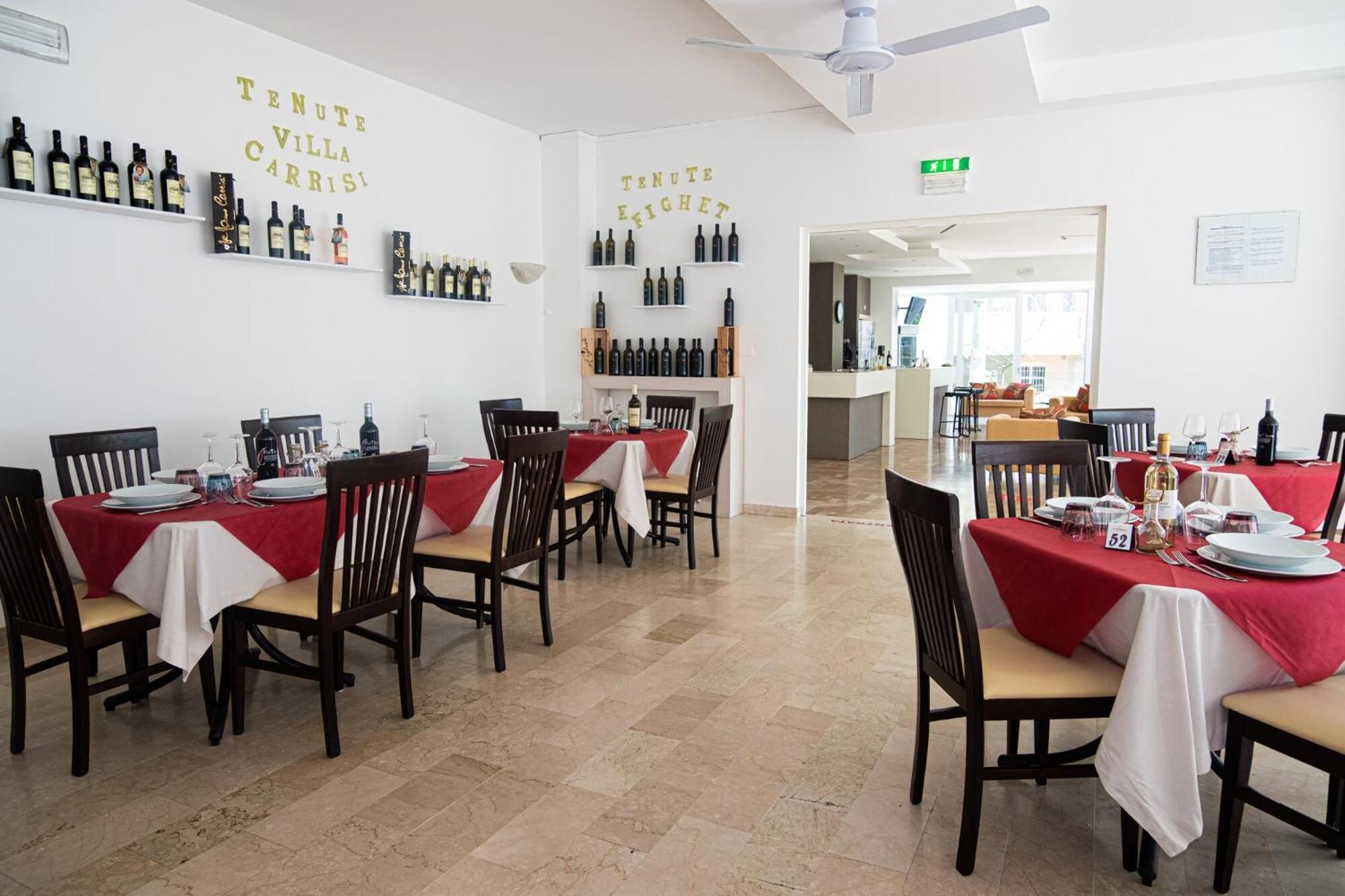 Un restaurante con varias mesas, cada una dispuesta con platos, vasos y botellas.