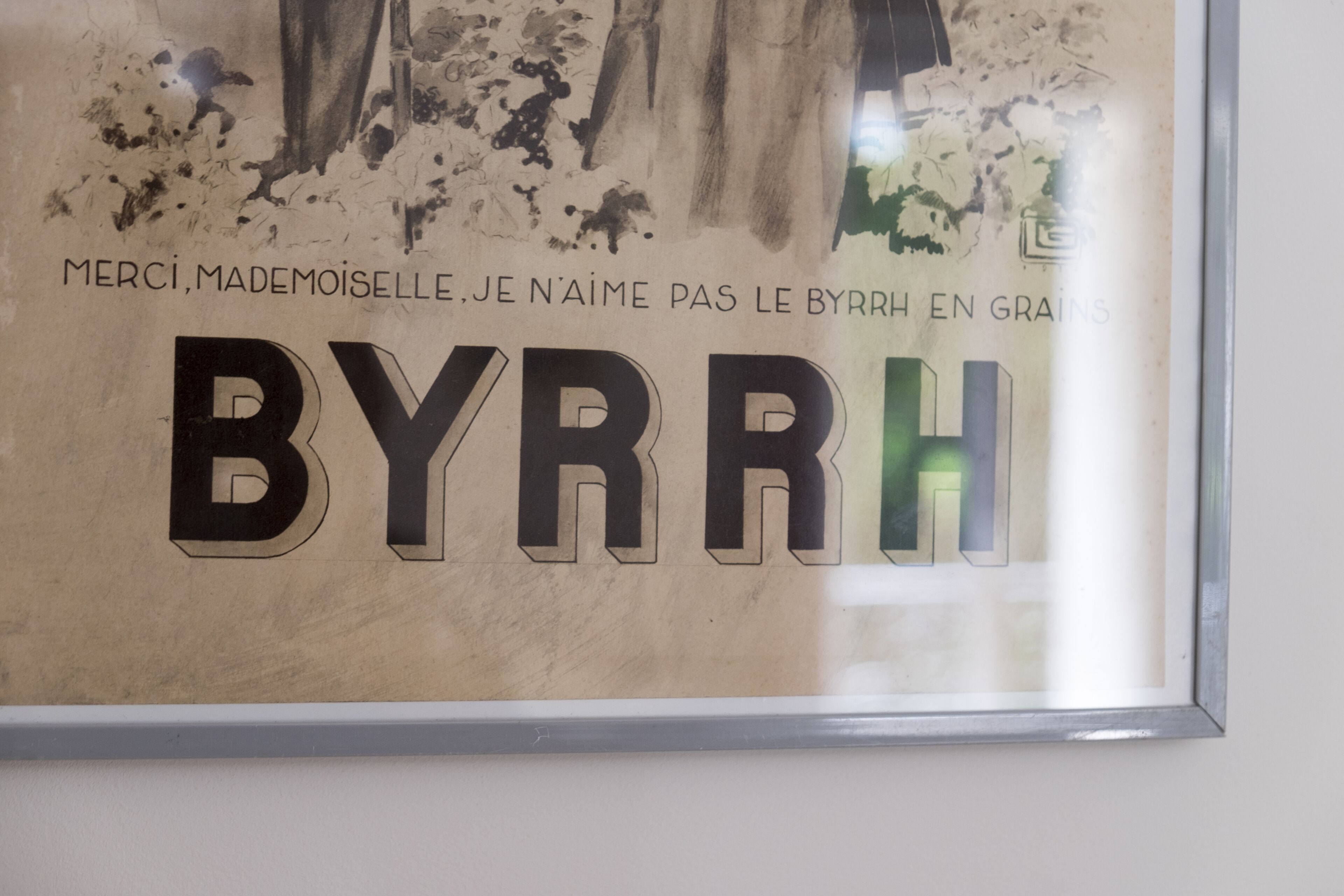 Une affiche encadrée avec le texte « MERCI, Mademoiselle. JE N’AIME PAS LE BYRRH EN GRAINS » et le mot « BYRRH » écrit en grandes lettres.