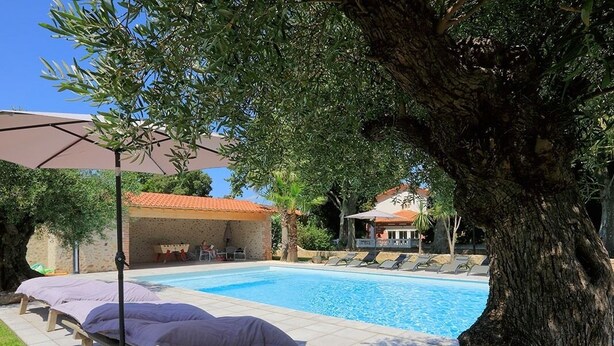 A swimming pool with lounge chairs and a pergola.