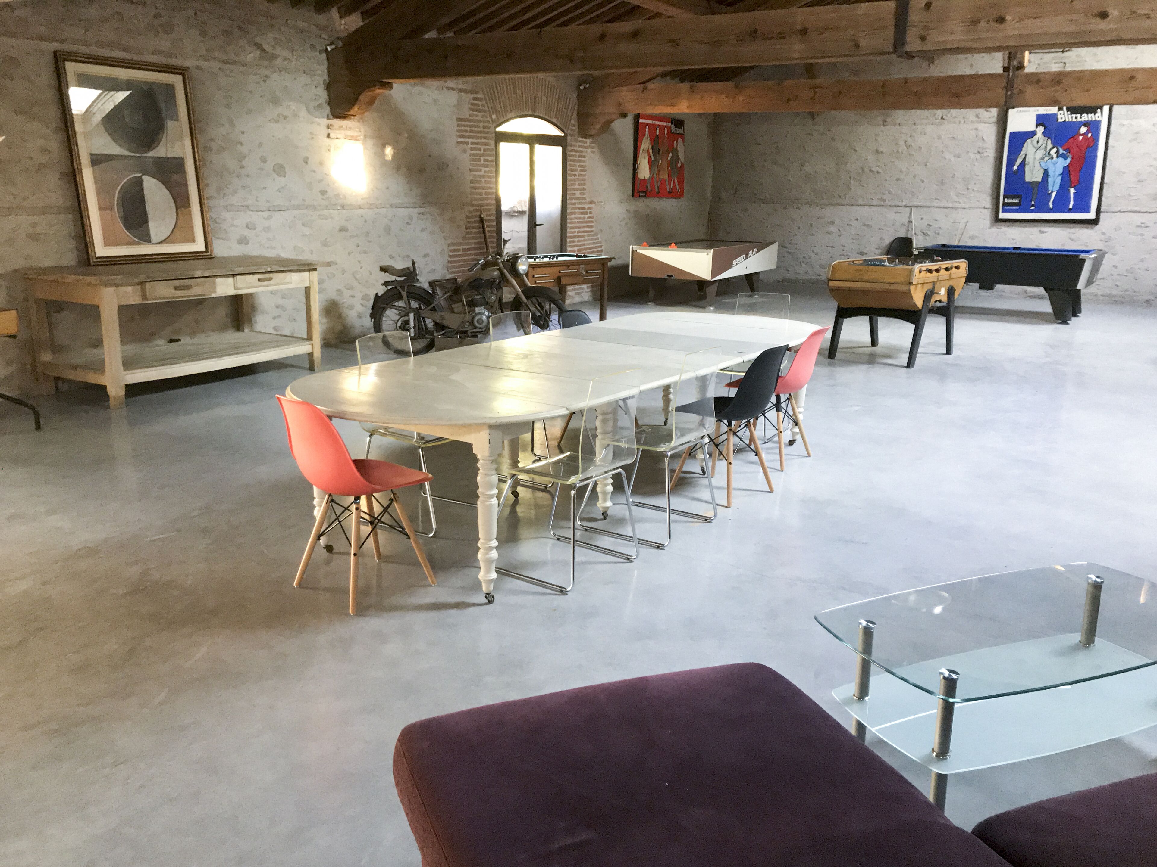 Una habitación amplia con una gran mesa de comedor, varias sillas, una mesa de billar y una motocicleta.