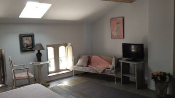 A bedroom with a bed, a chair, a television, a lamp, a window, and a painting on the wall.