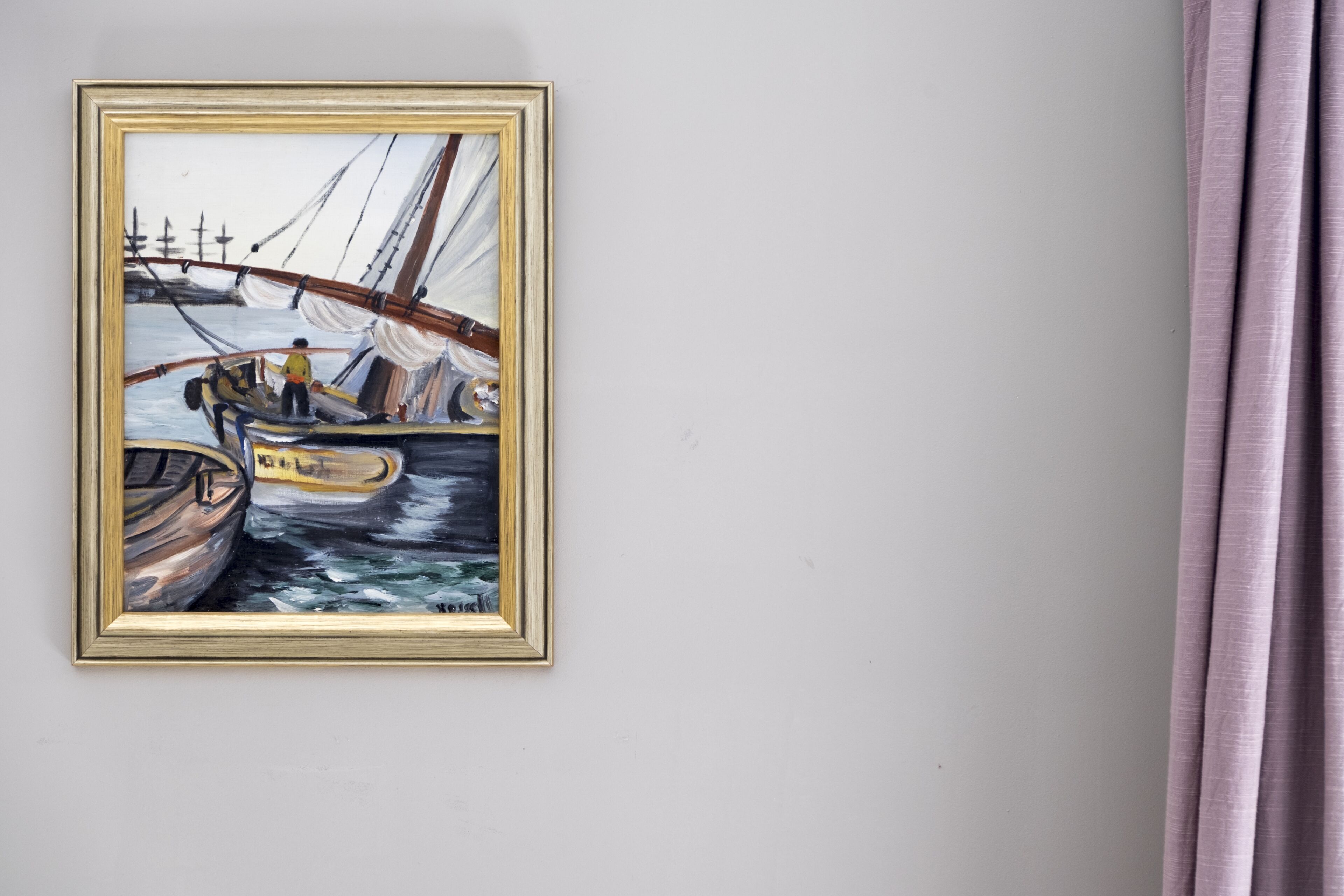 Un cuadro enmarco que muestra un barco a vela en una pared.