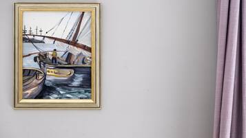 Un cuadro enmarco que muestra un barco a vela en una pared.