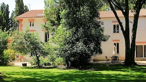 A building with a tiled roof, surrounded by a well-maintained lawn and trees.