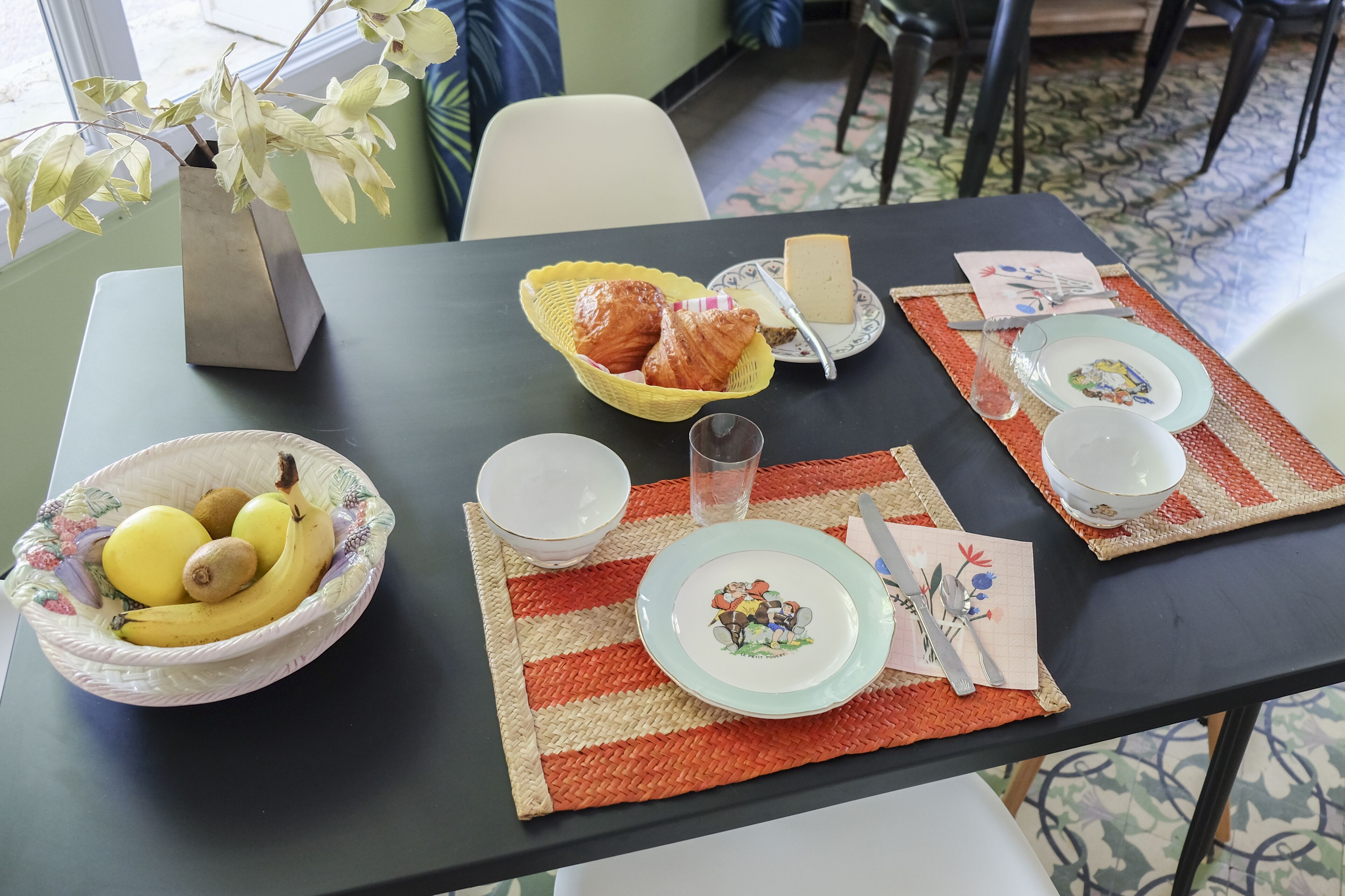 Een eettafel gedekt met borden, kommen en een vaas.