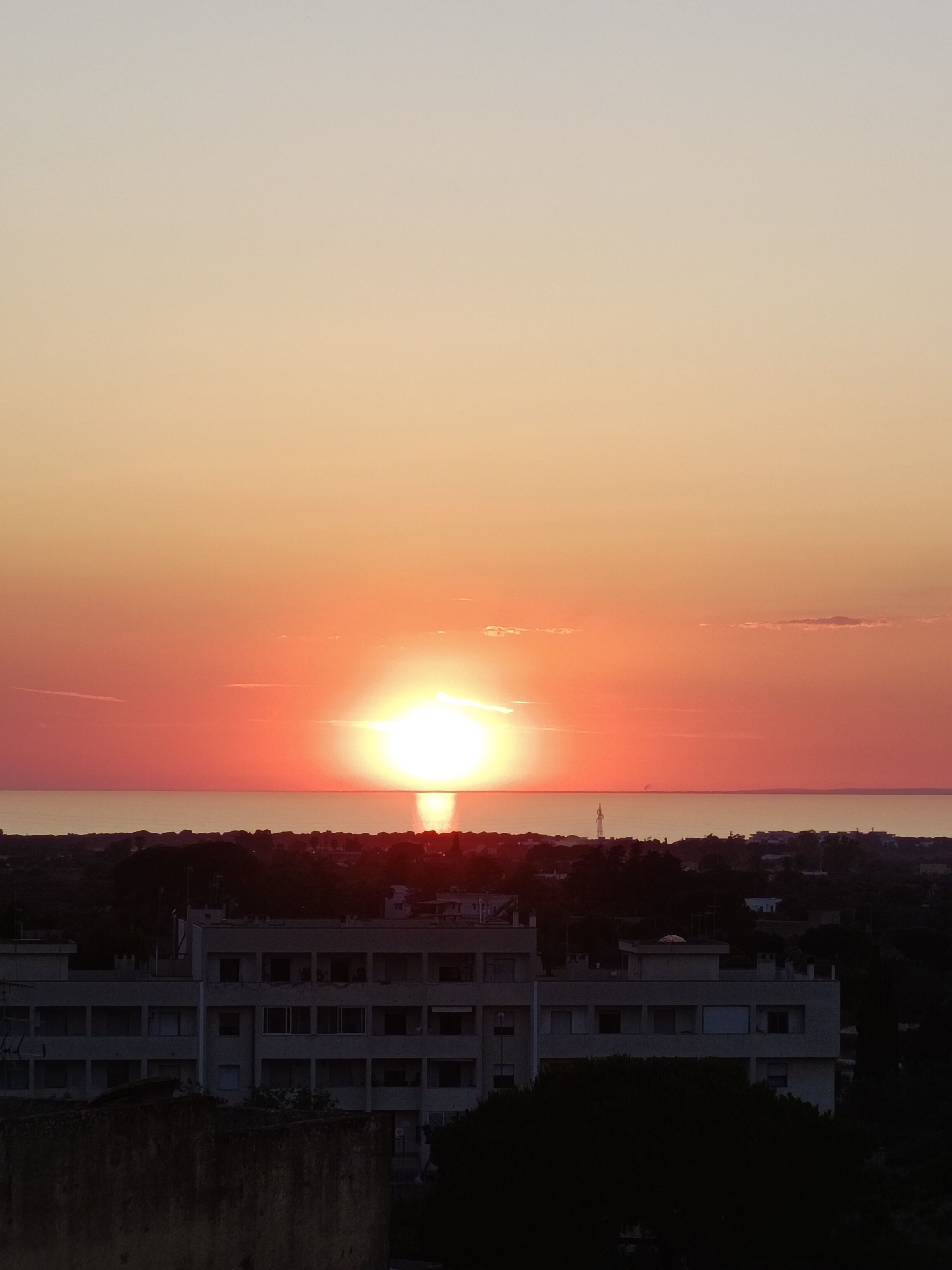 Un atardecer sobre una ciudad costera con edificios silueteados contra el cielo.