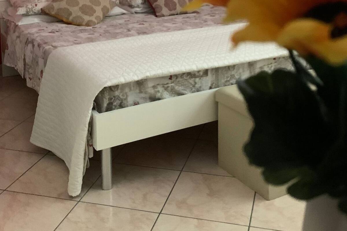 Un dormitorio con cama blanca, paredes rojas y una lámpara en el techo.