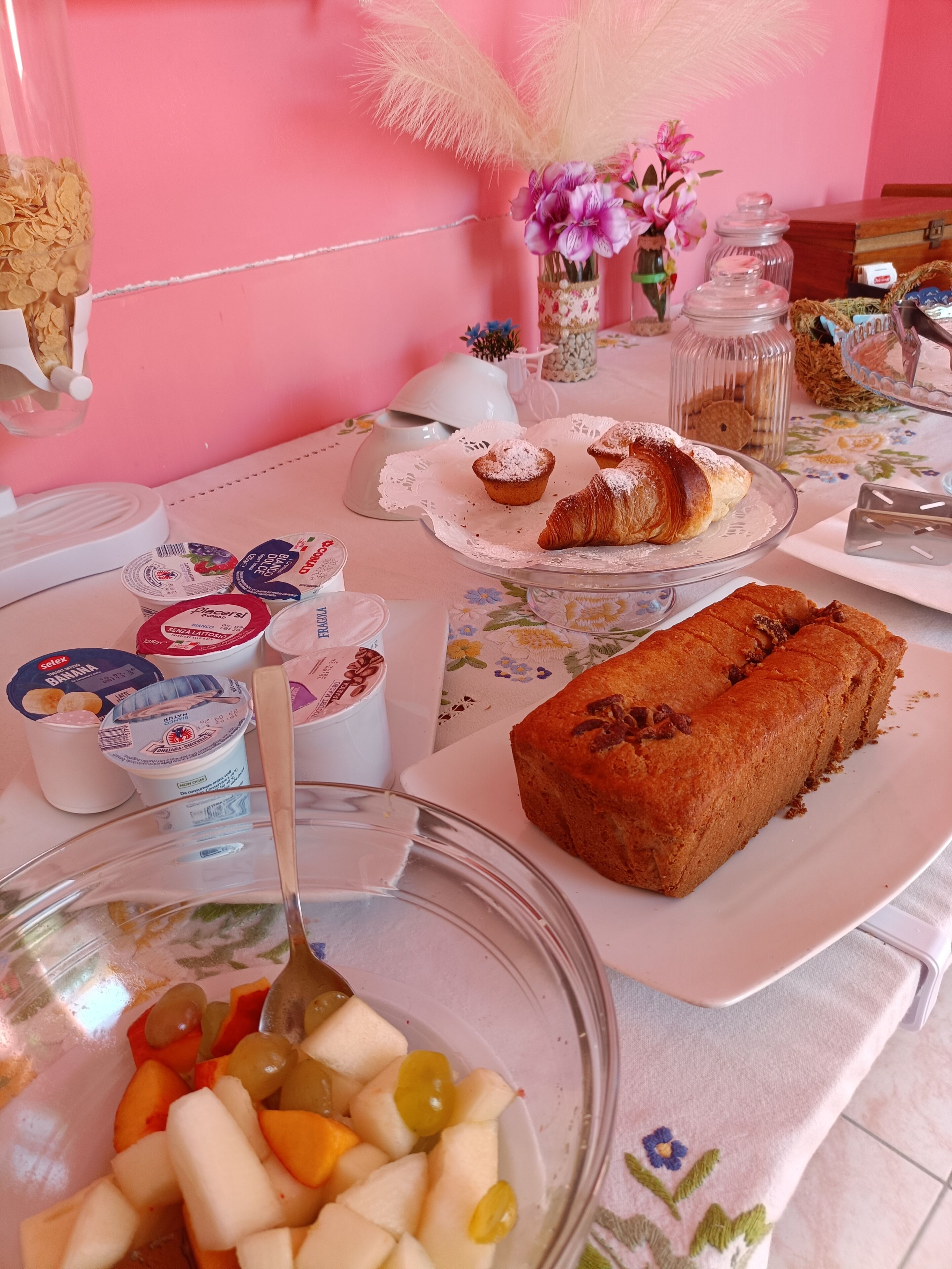 A breakfast table with various food items including pastries, fruit, and dairy products.