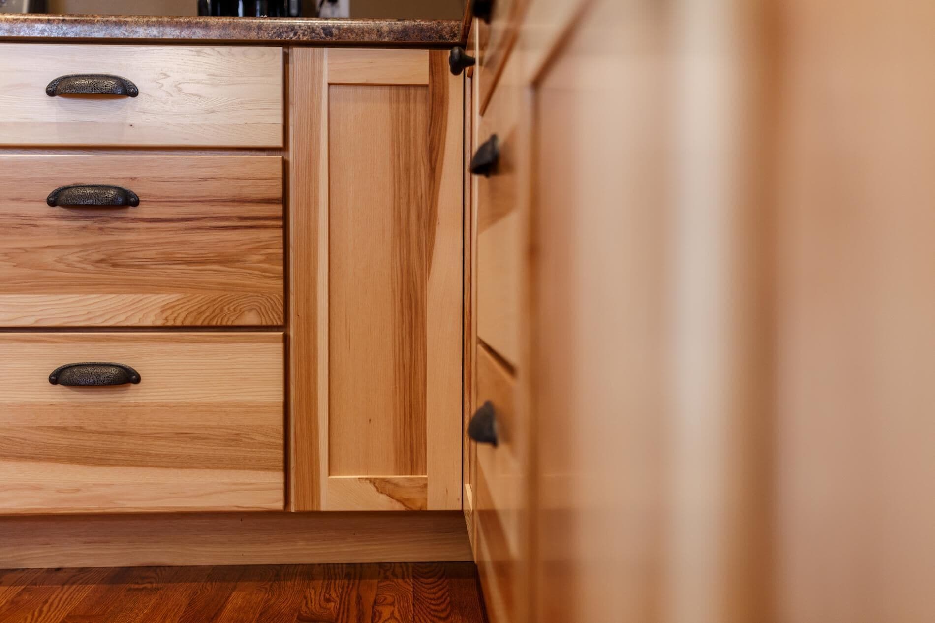 Un armario de cocina de madera con tres cajones y una puerta.