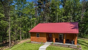 A log cabin with a red roof, a front porch, and a stone pathway leading to the entrance. - The Beautiful Whitetail Ridge-Luxury 5BR Cabin, Just minutes from downtown (Wisconsin Dells)