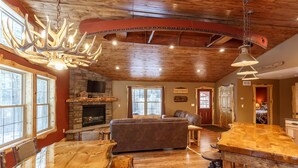 A spacious living area with a fireplace, a large wooden dining table, and a bar area. - The Beautiful Whitetail Ridge-Luxury 5BR Cabin, Just minutes from downtown (Wisconsin Dells)