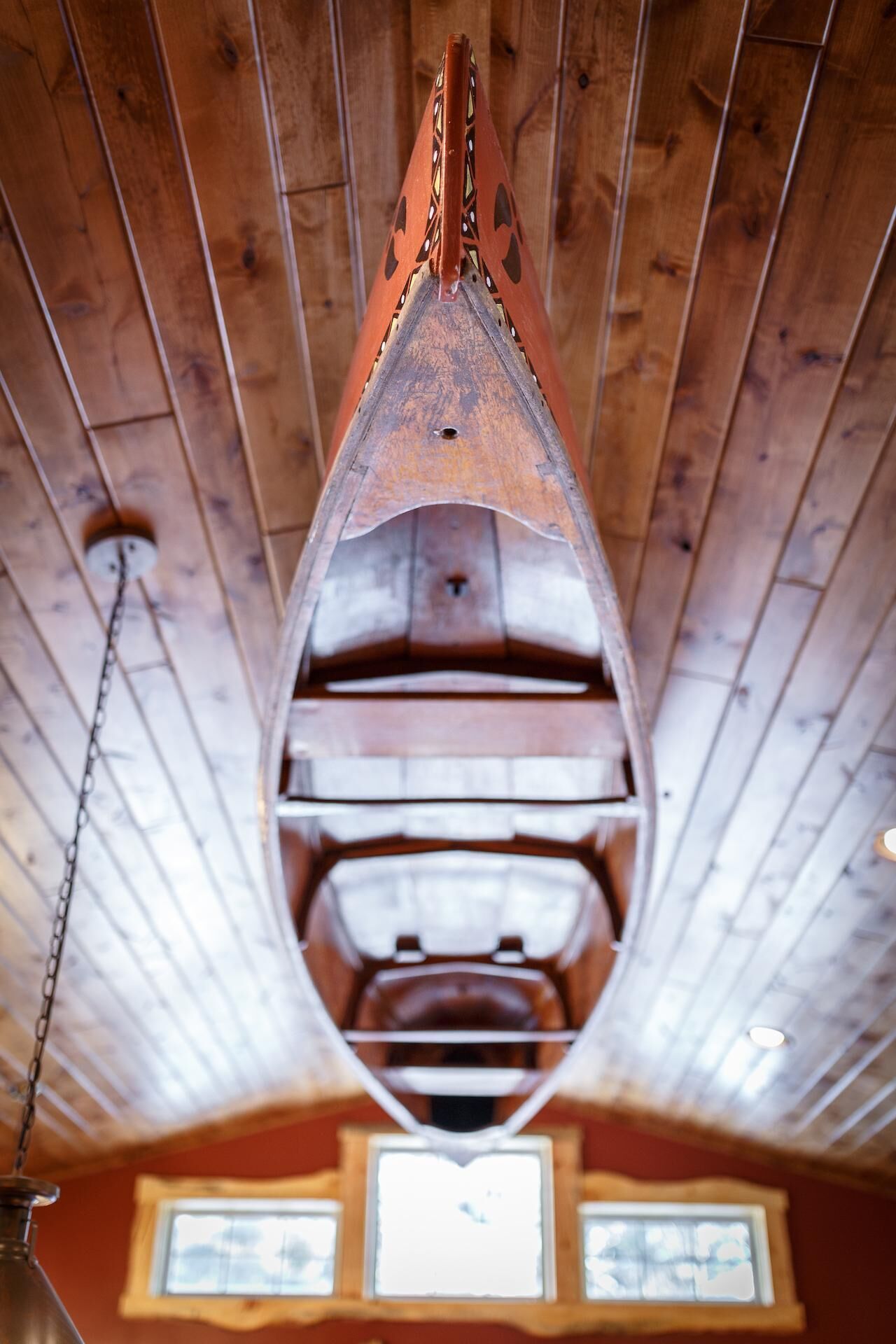 Un plafond en bois en forme de bateau, d’où pend une chaîne.