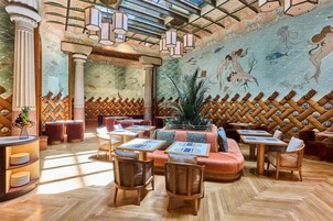 A restaurant interior with wooden furniture, a mural, and a wooden lattice wall.
