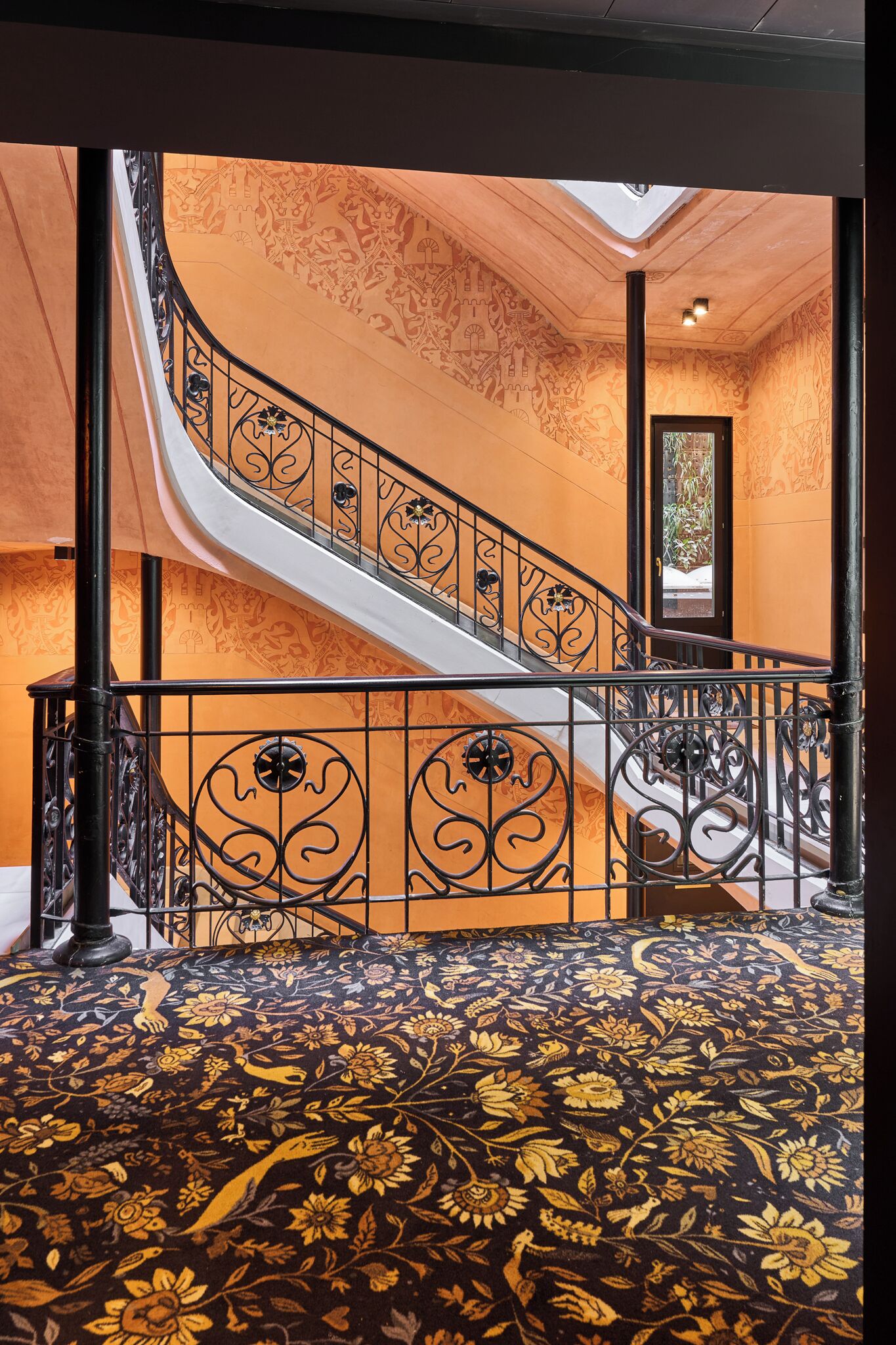 Una escalera con barandales negros ornamentados y un suelo con diseño.
