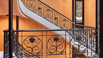 Una escalera con barandales negros ornamentados y un suelo con diseño.