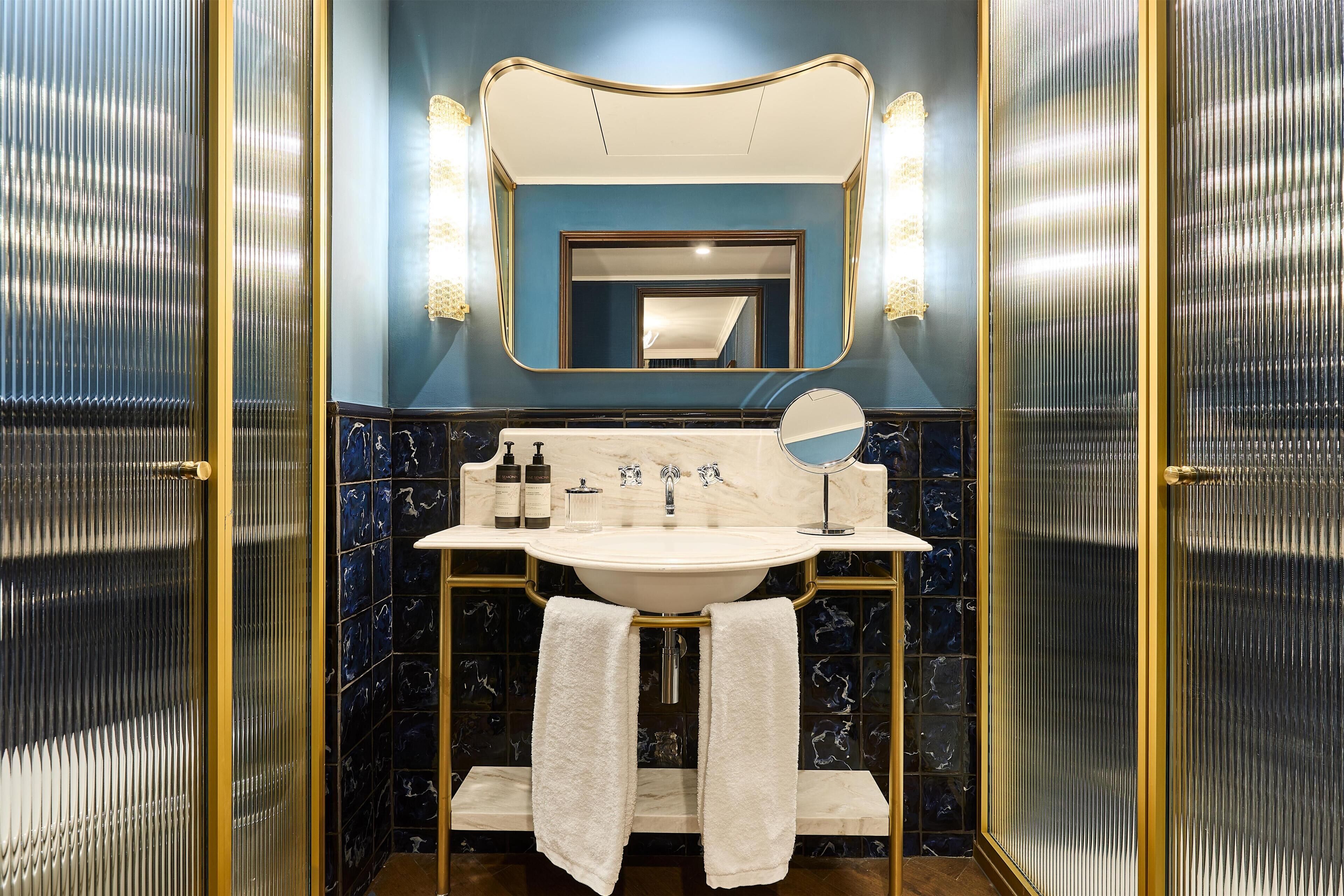 A bathroom with a marble sink, two towels, a mirror, and toiletries.