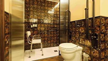 A bathroom with a white toilet, a shower area, and a chair.