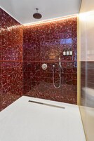 Une salle de bain moderne avec un espace douche, une baignoire blanche et un mur carrelé à motifs marbrés.