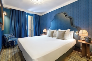 A hotel room with a large bed, a chair, a nightstand with a lamp, and a window with curtains. - Hotel España Ocean Drive (Barcelona)