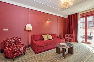 A red-themed room with a sofa, two armchairs, a floor lamp, and a coffee table.
