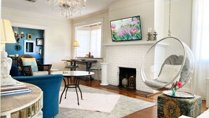 A spacious living room with a white brick fireplace, a hanging chair, and a dining area with a round table and chairs. - UPTOWN OASIS W PRIVATE, HEATED POOL, Minutes to all New Orleans' top attractions (New Orleans)