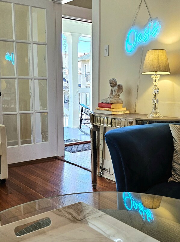 A room with a glass table, a blue sofa, a lamp, and a neon sign that reads "Oasis". - UPTOWN OASIS W PRIVATE, HEATED POOL, Minutes to all New Orleans' top attractions (New Orleans)