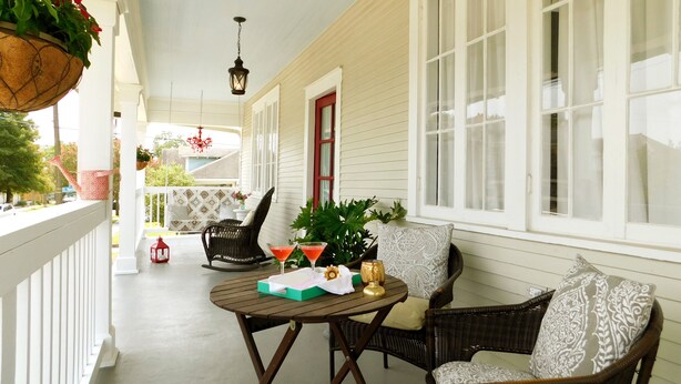 A covered porch with wicker furniture, a table with a drink, and hanging planters. - UPTOWN OASIS W PRIVATE, HEATED POOL, Minutes to all New Orleans' top attractions (New Orleans)