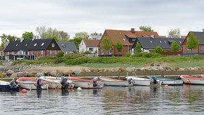A waterfront with several boats docked, houses with sloped roofs, and a rocky shoreline. - Branteviks Bed & Breakfast (Brantevik)