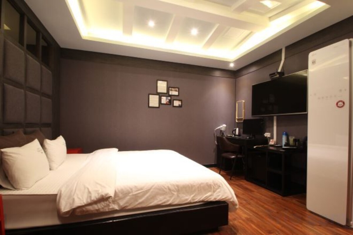 Une chambre moderne avec un lit, un bureau et un réfrigérateur.