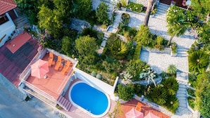Vue aérienne d’une propriété dotée d’une piscine, d’un espace salon extérieur et de jardins aménagés.