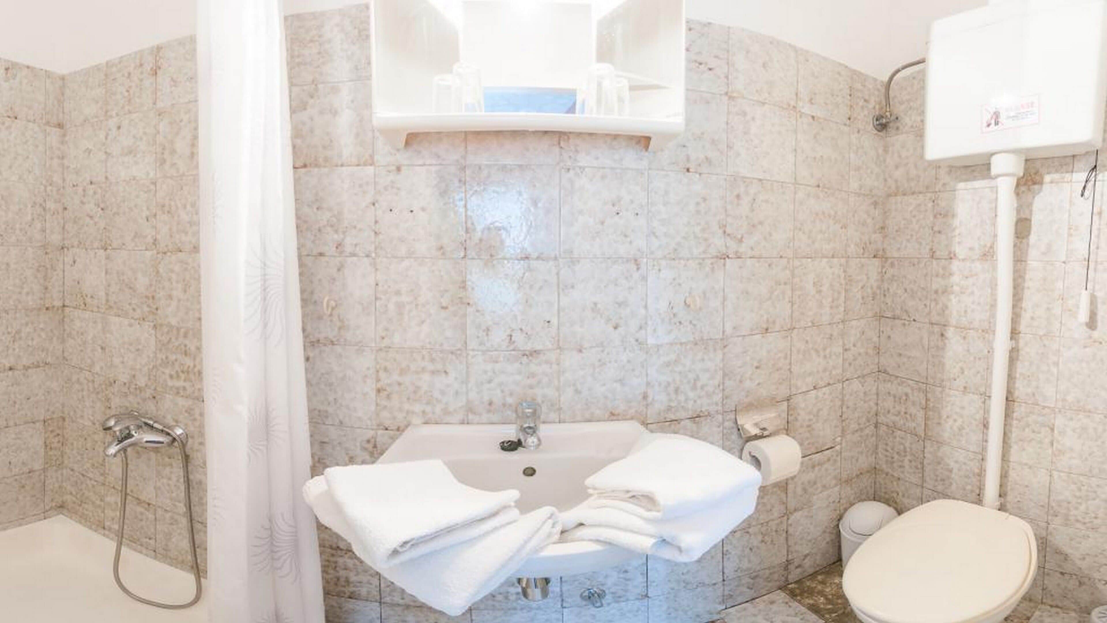 A bathroom with a shower, sink, and toilet.