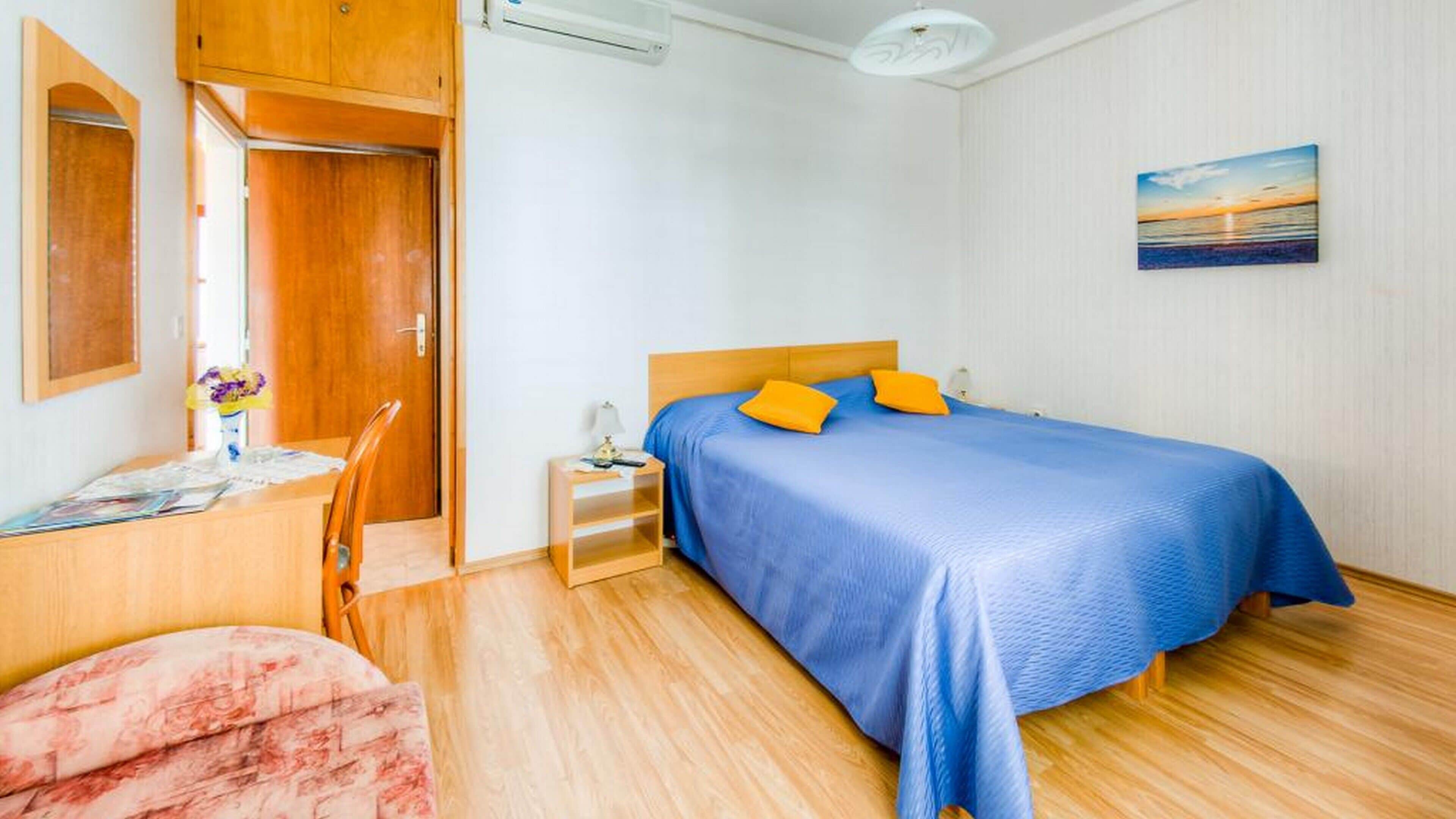 A bedroom with a bed, a desk, a chair, and a nightstand.