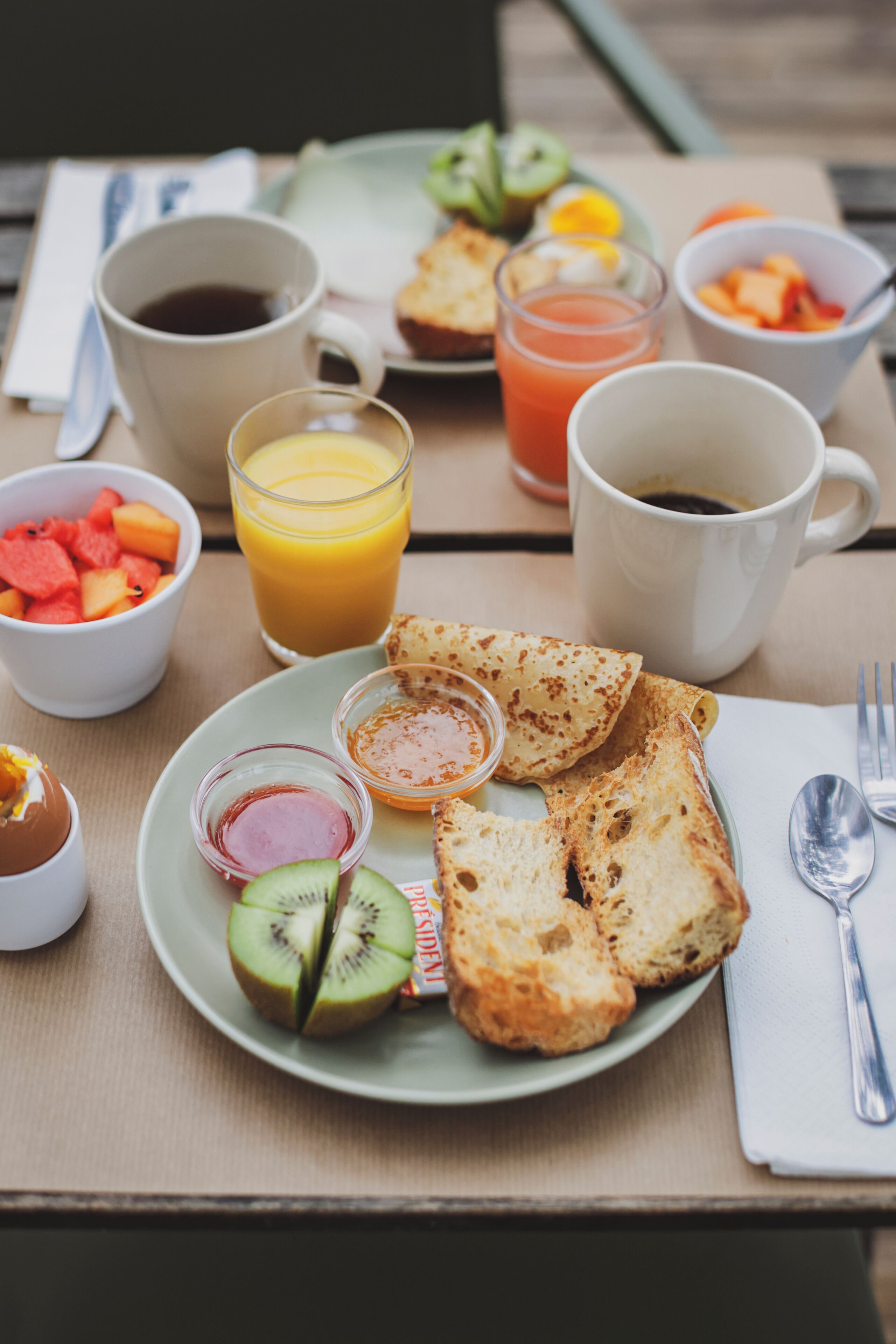 Una escena de desayuno con tostadas, fruta y bebidas sobre una mesa.