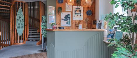 A reception desk with a wooden counter, framed artwork, and a clock on the wall.