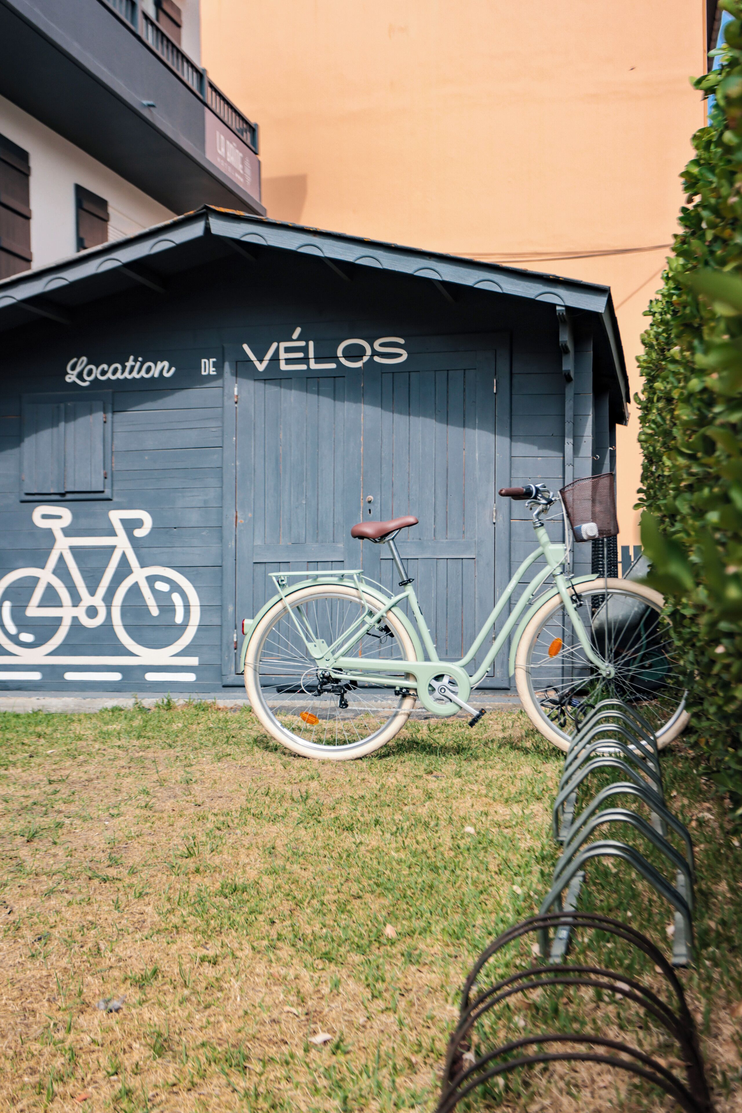 Uma bicicleta estacionada em frente a um edifício com uma placa que diz 'Location de VÉLOS'.