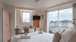 Habitación de hotel con una cama grande, un escritorio, una televisión y vistas a edificios.