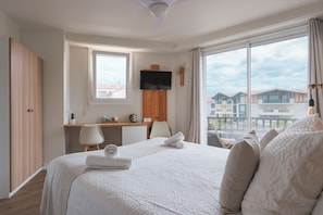 Habitación de hotel con una cama grande, un escritorio, una televisión y vistas a edificios.
