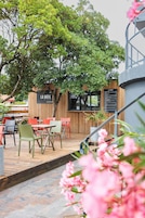 An outdoor seating area with tables and chairs, a wooden fence, and a sign for a pizza restaurant.