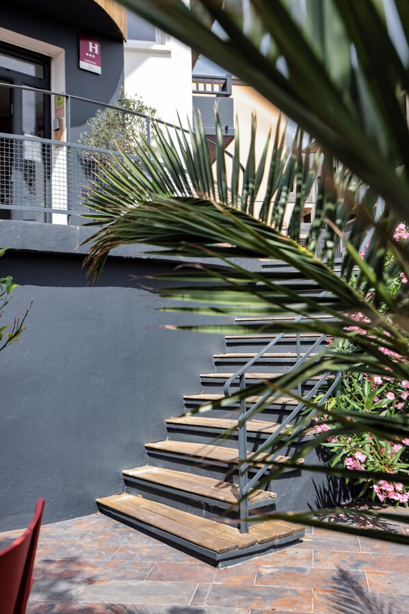 A staircase with wooden steps and metal railings, leading to a building with a 'H' sign. - Hôtel La Baïne (Capbreton)