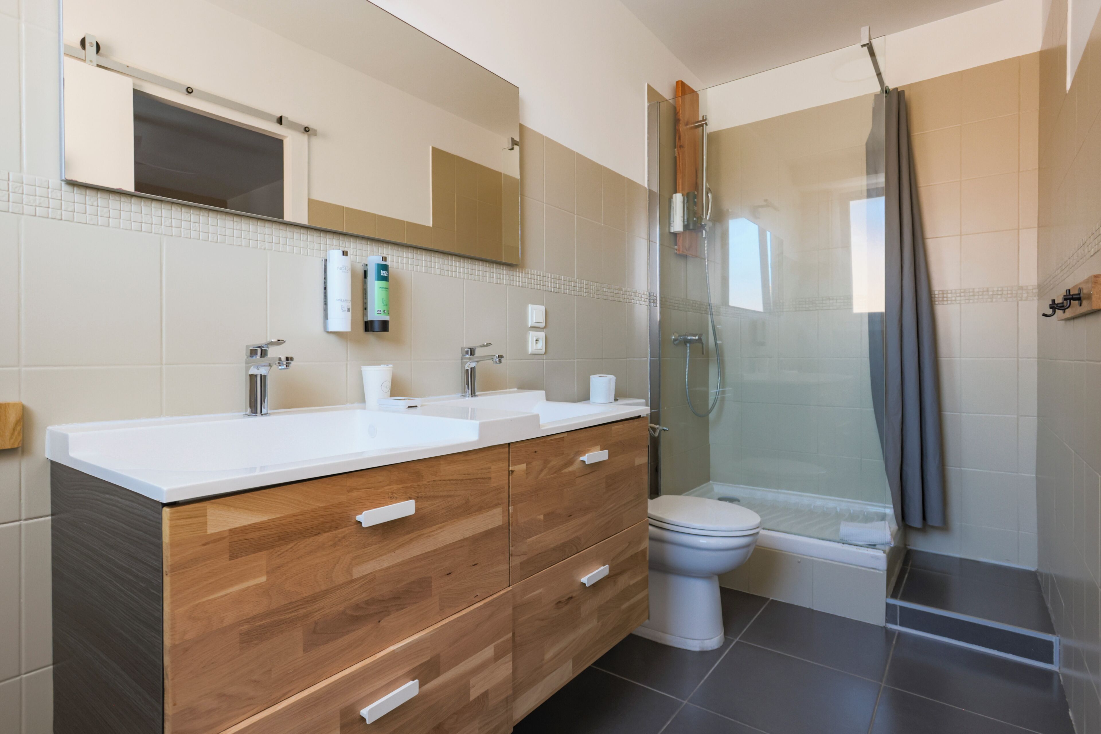 Ein modernes Badezimmer mit einem Holzkosmetikschrank, einer Glasdusche und einer Toilette.