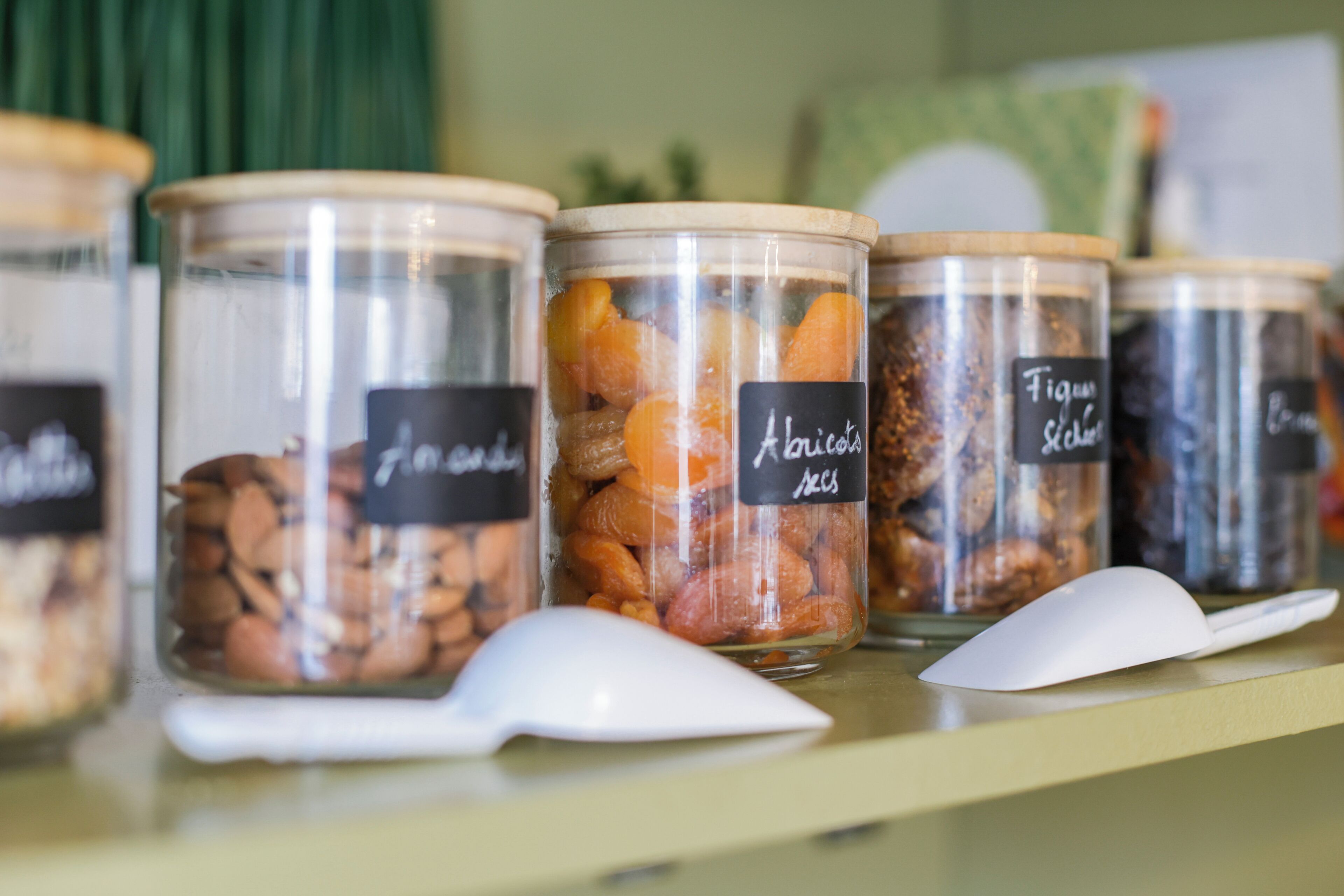 A row of glass jars with labels on a shelf.