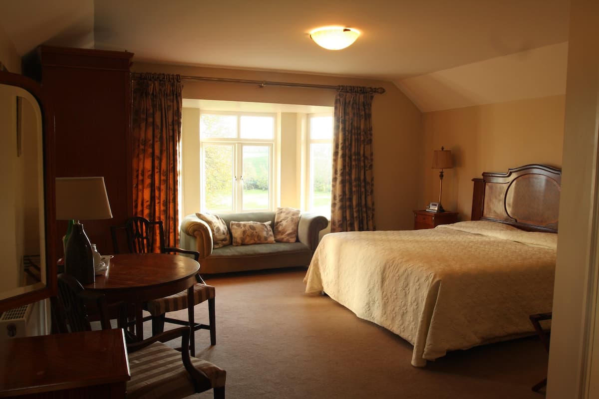A bedroom with a bed, a sofa, a table, and a lamp.