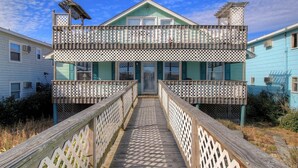 A two-story house with a wooden deck leading to a glass door entrance.