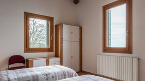 Un dormitorio con dos camas, un escritorio, una silla y un armario.