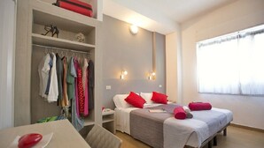 Ein Hotelzimmer mit Bett, Nachttischen, einem Schrank und einem Fenster mit Vorhängen.