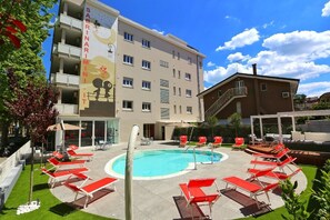 Una piscina al aire libre de temporada, sombrillas, tumbonas