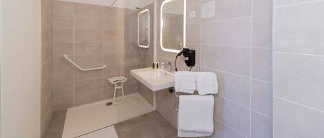 A modern bathroom with a shower, sink, and mirror.