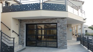 Un bâtiment à deux étages doté d’une façade en pierre, d’une entrée en verre et d’un balcon avec une rambarde en métal.