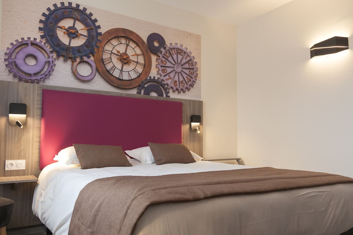 Une chambre moderne avec un grand lit, une tête de lit rouge et des horloges décoratives au mur.