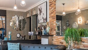 Un salon moderne avec un canapé en cuir, des miroirs décoratifs, des horloges et une grande plante.
